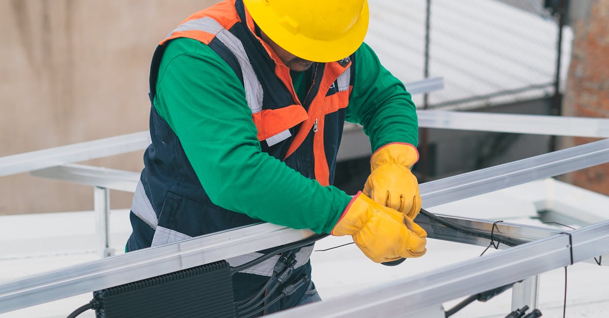 Electrician with PPE working on rooftop solar panel installation, focusing on safety.